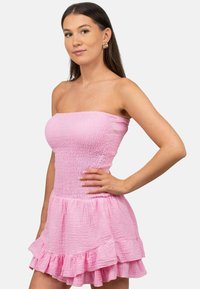 Strapless roze jurk van textuurstof, met een aansluitende bovenkant en een uitlopende rok met een gerimpelde zoom.