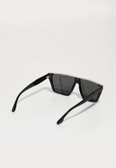 Mustad mustad geometrilise kujuga prillid, tumedad läätsed ja kuldne aktsent ülemisel raamile. Omab stiilseid musti tempesid.