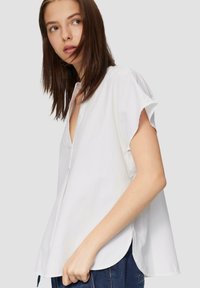Witte short-sleeve shirt met een diepe V-hals, knoopsluiting en een ronde zoom. Gemaakt van een gladde, lichte stof met een casual fit.