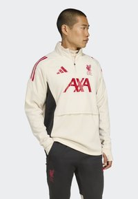 Hvid og sort atletisk jakke med røde detaljer, prydet med en lynlåskrave, broderet logo og kontrasterende paneldesign.