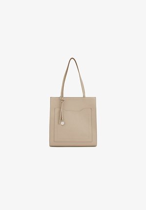 Beige leren tote bag met een vlakke vorm, dubbele schouderbanden, een voorzak en een decoratieve charme bevestigd aan een dunne band.