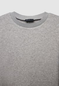 Hellgrauer Pullover mit ribbelndem Rundhalsausschnitt. Der Stoff hat eine dezente Textur, und ein Etikett auf der Rückseite trägt die Aufschrift "CALLIOPE S."