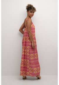 Rosa maxiklänning med blommönster som har gula accenter, tunna axelband och en lös passform. Det lätta tyget faller ner till anklarna.