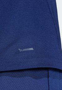 Jūros laivyno sportinė marškinėliai su lygiu audiniu, puoštos ClimaCool logotipu šalia apatinės dalies; apima tekstūruotą tinklinį skyrių oro pralaidumui.