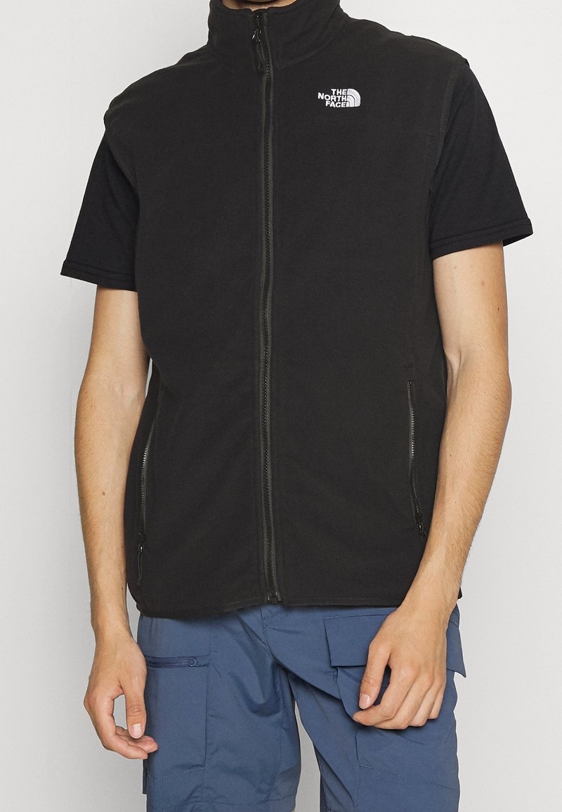 Schwarze ärmellose Fleece-Weste mit hohem Kragen, Frontreißverschluss und zwei seitlichen Taschen. Logo auf der oberen linken Seite. Strukturiertes Gewebe.