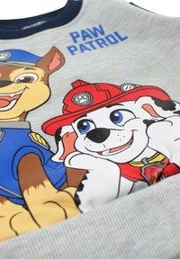 Sweat-shirt gris avec des personnages de dessins animés de "Pat' Patrouille". Le design comprend un col rond bleu, des imprimés vibrants et une texture douce.