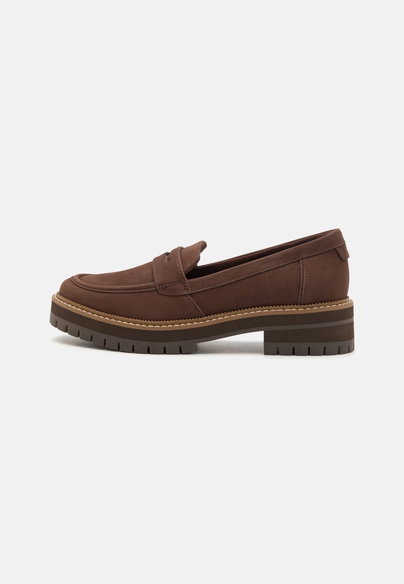 Mocassin en cuir marron avec semelle épaisse à crampons et petit talon carré, doté d'une lanière cousue sur le dessus.
