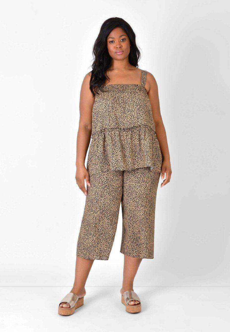 Brun leopardmönstrad ensemble bestående av en peplumtop med spaghettistöd och vida cropped byxor, matchat med plattformssandaler.