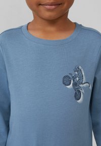 Blauwe sweatshirt met een ronde halslijn en lange mouwen, afgewerkt met een grafische afbeelding van een tijger op een motor, geborduurde tekst "BIG SHOW."