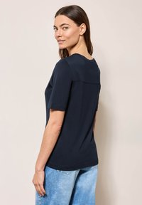 Mørkeblå kortærmet T-shirt med rund halsudskæring og rygl�ænderdetalje, lavet af blødt stof, parret med lyseblå denimshorts.