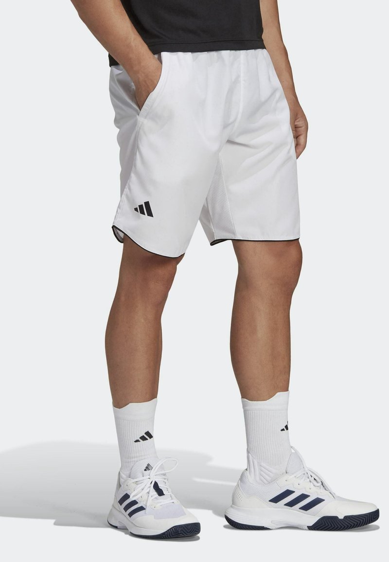 Vita idrottsshorts i vitt med svarta kanter och Adidas-logotyp. Shortsen har två sidofickor och är tillverkade av ett lätt material för komfort.