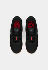 Black athletic shoes with a mesh design, red insoles, and gum rubber outsoles. Features laces and a logo on the heel and tongue.