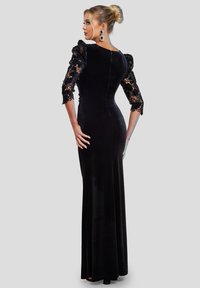 Zwarte fluwelen avondjurk met een nauwsluitende pasvorm, kanten pofmouwen en een rits aan de achterkant. Vloerlengte ontwerp met een gladde textuur.