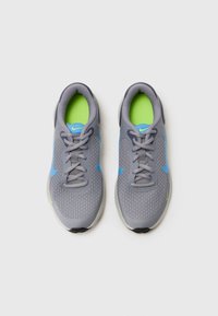 Des chaussures de sport grises avec un dessus en maille, des accents bleus et une semelle intérieure verte. Elles disposent de lacets ronds et d'une semelle rembourrée pour le confort.