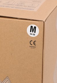 Brun pappkartong med en vit cirkulär etikett som anger "M 54-58" och CE-certifiering. Texturerad yta, ren design och inga ytterligare mönster synliga.