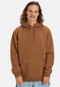 Brown hoodie made of soft fabric, featuring a front pocket, drawstring hood, and a small black logo patch on the chest.