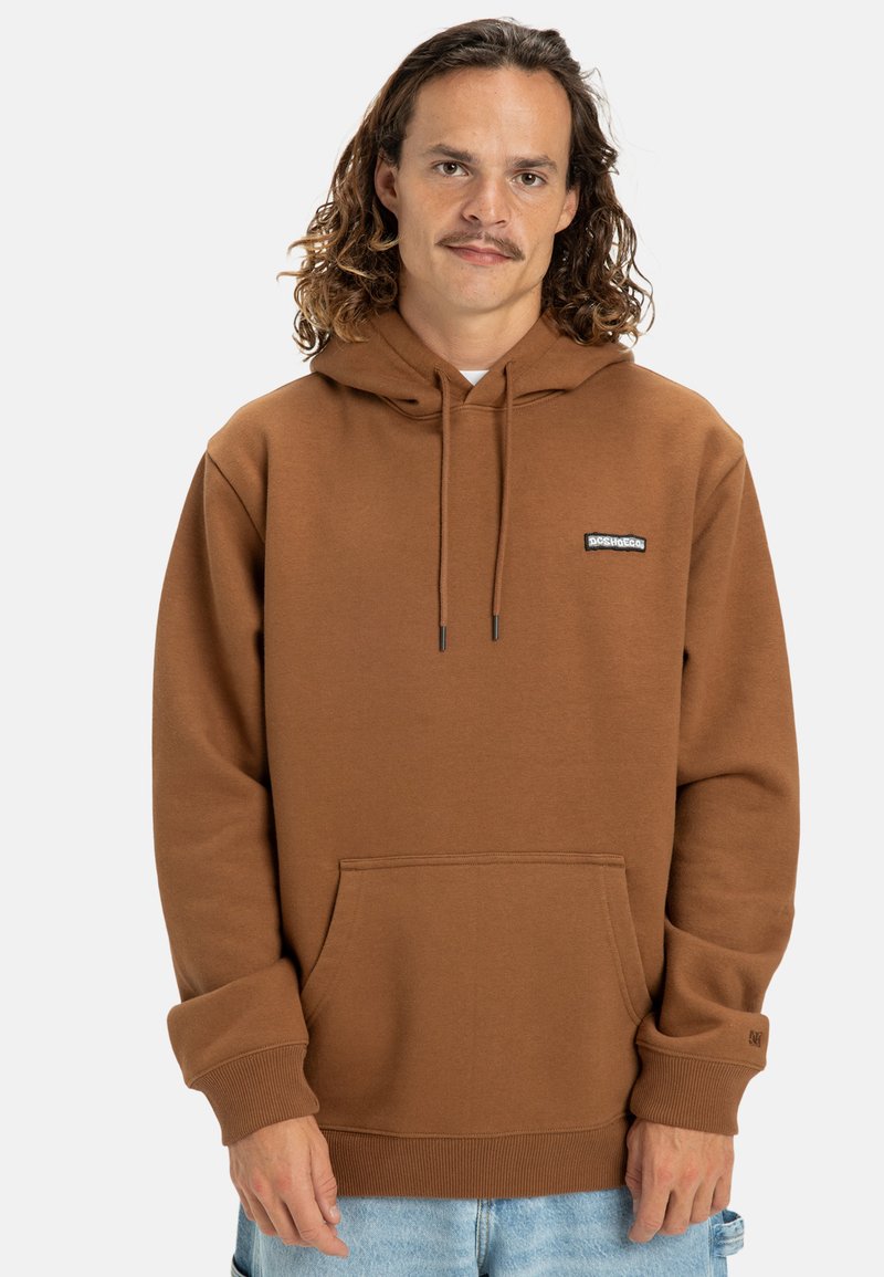 Brown hoodie made of soft fabric, featuring a front pocket, drawstring hood, and a small black logo patch on the chest.