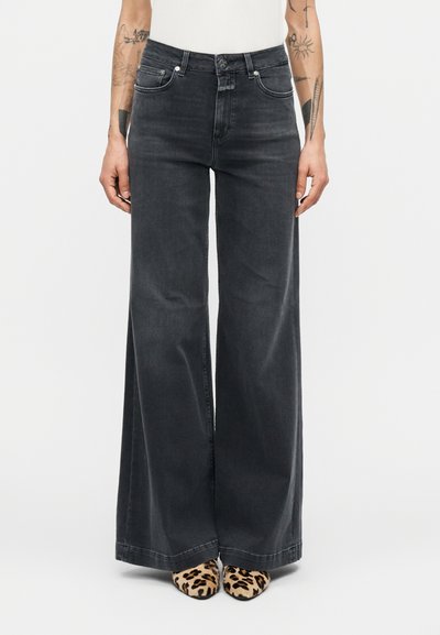 Jean denim noir à jambes larges avec une taille haute, doté de poches avant et d'une texture lisse. Associé à des chaussures à bouts pointus imprimé léopard.