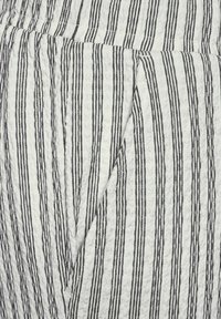 White fabric with black vertical stripes, textured surface, featuring a diagonal pocket detail on the left side.