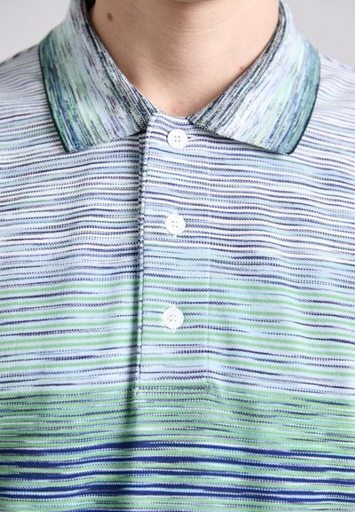 Polo krekls ar apkakli, ar horizontālām svītrām zaļā, zilā un baltā krāsā. Satur trīs baltas pogas gar plati un faktūru audumu.