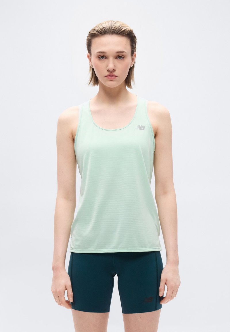 Νέος με κοντά μαλλιά, φορώντας αμάνικο αθλητικό τοπ σε ανοιχτό πράσινο και σκούρα μπλε σφιχτά σορτς, σε απλό λευκό φόντο.