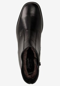 Bottine en cuir noir à la texture lisse, avec des panneaux élastiques sur les côtés et une fermeture éclair. L'intérieur doublé offre de la chaleur. Design épuré avec un embout légèrement pointu.