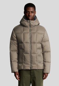 Lichtbruine pufferjack met capuchon, voorzien van een quilted ontwerp, een rits aan de voorkant en zijzakken. De textuur is soepel en gewatteerd.