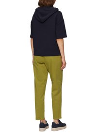 Granatowa, prążkowana bluza z krótkim rękawem i kapturem, w zestawieniu z jasnoszarymi, zwężanymi spodniami. Uzupełnieniem stroju są granatowe trampki z beżową podeszwą.