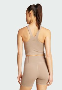 Top corto atlético beige y pantalones cortos a juego, elaborados con una tela suave y elástica, con un diseño de espalda deportiva y un detalle de logo en la parte posterior.