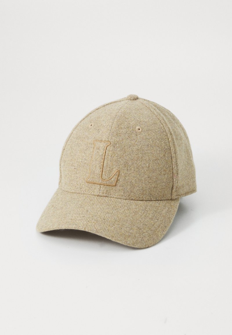 Beige gyapjú baseball sapka ívelt karimával, amelynek elülső részén egy világosabb árnyalatú „L” betű van hímezve. Finom textúrával rendelkezik és hatszögletű kialakítású.