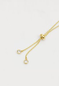 Collar de cadena de oro con dos gemas circulares transparentes en los extremos. Cuenta con un cierre redondo y suave ajustable para modificar la longitud.