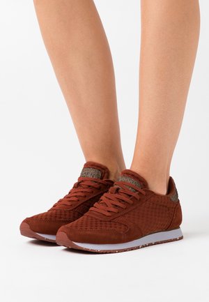 Scarpe sportive rosse realizzate in mesh strutturato e suede con colletto imbottito, dotate di una suola intermedia grigia e lacci abbinati.