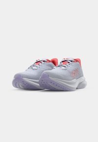 Baskets de sport gris clair avec une surface texturée, des accents rouges sur le talon et la languette, des lacets blancs et un design de semelle extérieure violet.