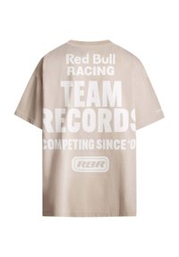 Helles beiges T-Shirt aus Baumwolle mit großen weißen Text: "Red Bull Racing TEAM RECORDS COMPETING SINCE 'O," und einem Logo darunter. Kurze Ärmel.