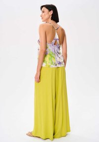 Bloemen tanktop met paarse en groene patronen, verstelbare schouderbanden en een keyhole achterkant, gecombineerd met wijde limoen groene broek.