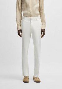 White tailored trousers made of lightweight fabric, featuring a smooth texture and a straight fit. Paired with a light beige button-up shirt.
