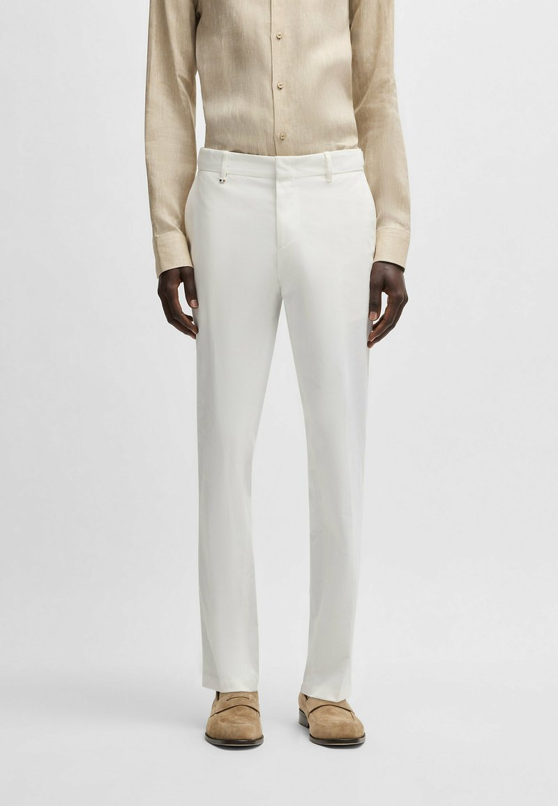 White tailored trousers made of lightweight fabric, featuring a smooth texture and a straight fit. Paired with a light beige button-up shirt.