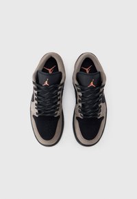 Ζευγάρι μαύρα και γκρι αθλητικά παπούτσια Nike Air Jordan με μαύρα κορδόνια και κόκκινα λογότυπα Jumpman στη γλώσσα και την πέλμα, σε θέα από πάνω.