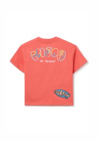 Camiseta corta de color rosa coral con mangas cortas, que presenta texto multicolor en la parte posterior: "DISFRUTA DEL MOMENTO" y un pequeño gráfico de "SURFIN'".