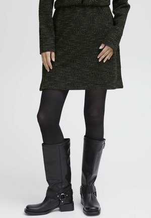 Black knee-high leather boots with a low, chunky heel. Features a buckle accent and smooth texture. Paired with a textured dark skirt.
