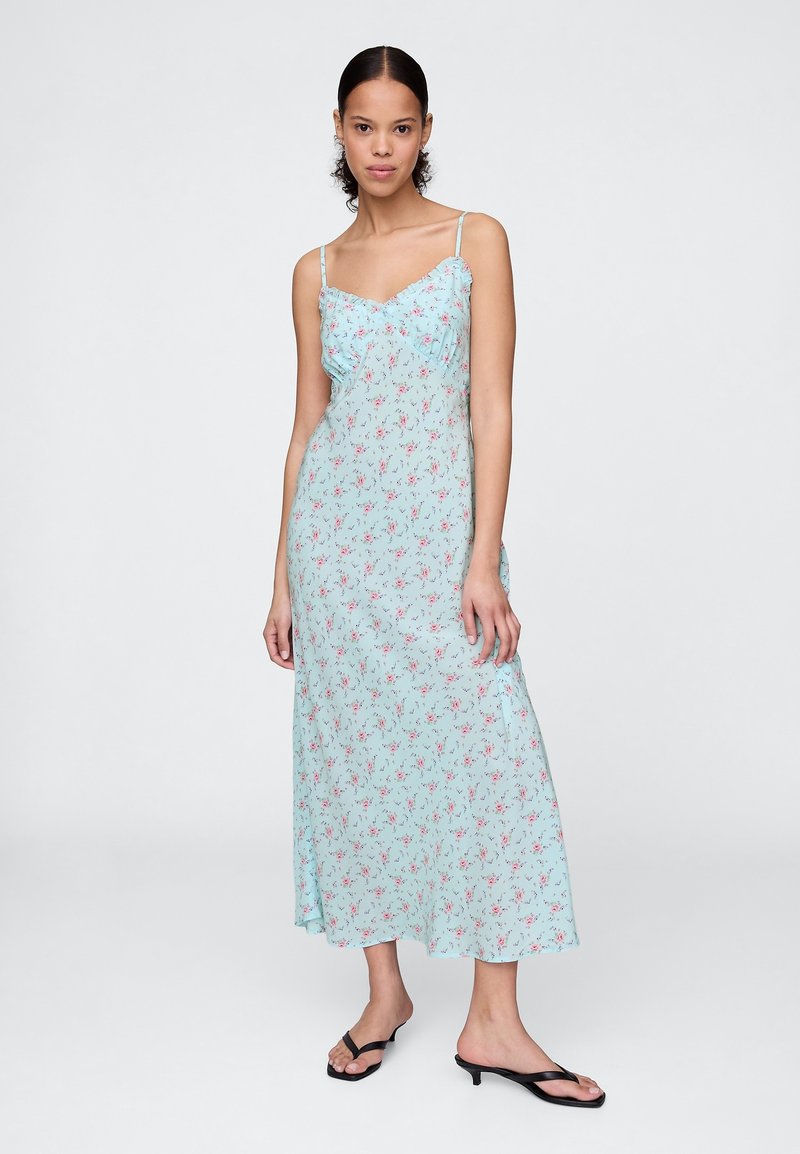 Vestido floral azul claro com alças finas, comprimento médio, apresentando um corpete com folhos e pequenos padrões florais em vermelho e rosa por todo o vestido.