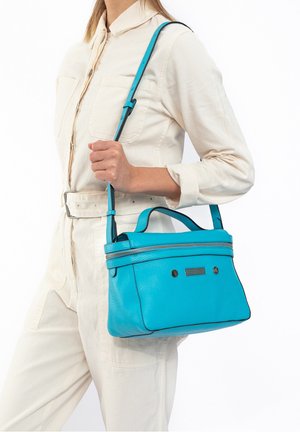 Turquoise leren handtas met dubbele ritssluiting, rechthoekige vorm en contrasterende stiksels. Voorzien van een afneembare schouderband en korte handvatten.