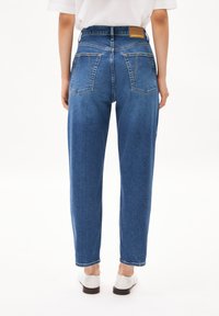 Hoge taille blauwe denim jeans met een rechte snit, voorzien van twee achterzakken en een bruine merklabel bij de tailleband.
