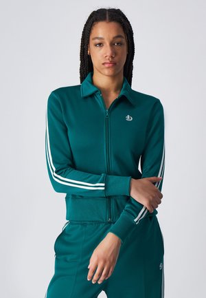 Giacca da tracksuit con zip di colore teal, con accenti a strisce bianche sulle maniche, tessuto testurizzato e un logo sul petto. Design aderente con colletto.
