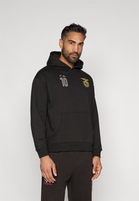 Crna dukserica od mješavine pamuka, s kengurskim džepom, rebrastim manžetama i zlatnim izvezenim logotipom i brojem 10 na prsima.