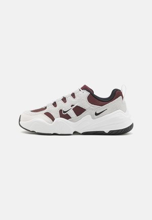 Scarpe da ginnastica con tomaia in pelle scamosciata bianca e grigia, accenti in mesh color bordeaux, suola in gomma nera e un logo Nike evidente sul lato.