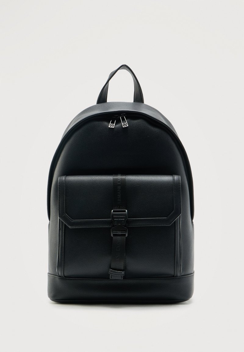 Μαύρο δερμάτινο σακίδιο με μπροστινή θήκη ασφαλισμένη με λουρί και αγκράφα και διπλό φερμουάρ στο κύριο διαμέρισμα, όρθιο σε λευκό φόντο.