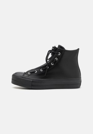 Sneaker alte nere con una parte superiore in gomma liscia, punta rotonda, occhielli in metallo e lacci neri piatti. Suola in gomma texturizzata per una migliore aderenza.