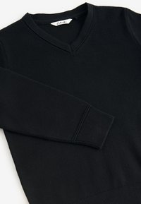 Črn bombažni pulover z V-izrezom, rebrastimi manšetami in teksturiranim zaključkom. Oznaka na ovratniku z napisom "Clarks."