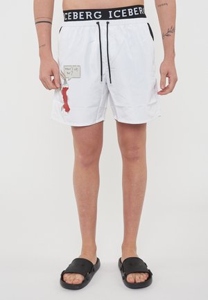 Costume da bagno bianchi con coulisse nera, che presenta un'immagine cartoni animati e il testo "Che succede, Dottore?" sul lato sinistro. Vita con logo nera.